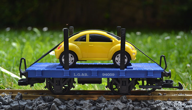 желтую машинку перевозят по железной дороге